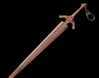 May include: A rose gold sword keychain with intricate details and a decorative handle. The keychain is made of metal and has a ring for attaching to keys.