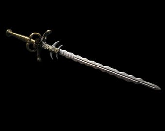 May include: A decorative sword with a silver blade and ornate gold-colored hilt. The blade has a wavy design, and the hilt features intricate scrollwork and a detailed hand guard. The sword is set against a black background.