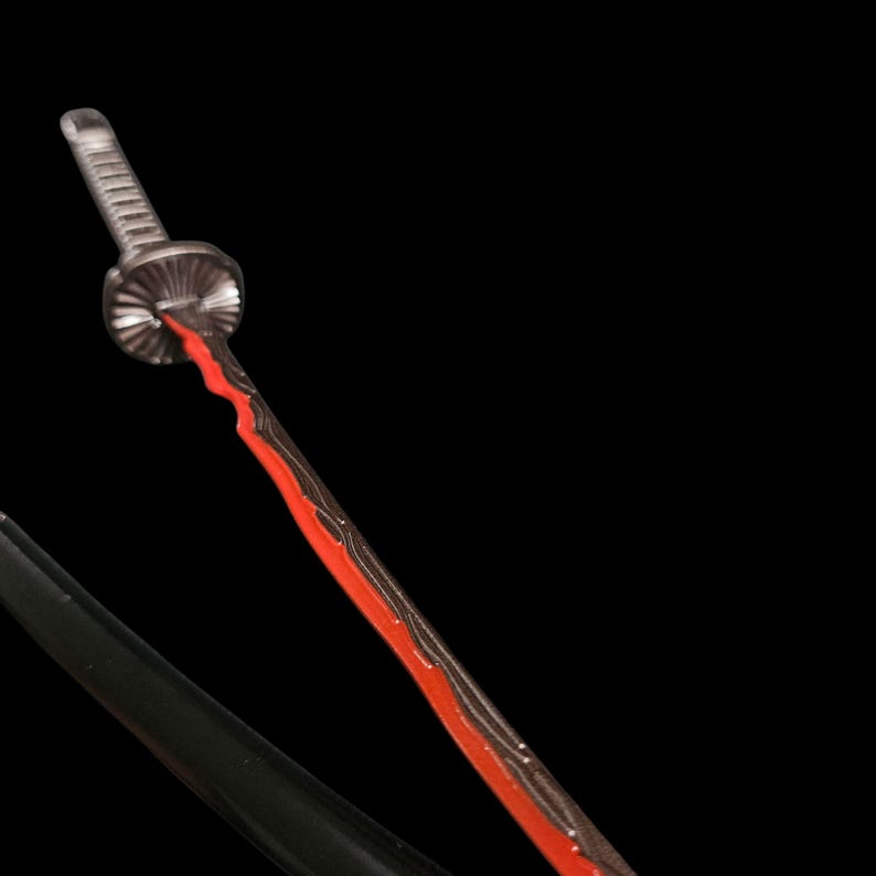 May include: A detailed image of a katana sword with a black handle and a blade featuring a striking red and black design. The sword's guard is silver, and the blade has a unique, wavy pattern. The background is solid black.