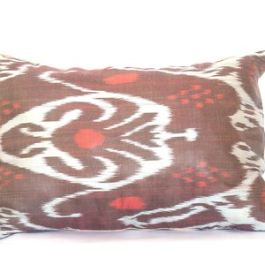 Peut inclure: Un oreiller rectangulaire en tissu doux et tissé, avec un motif brun et blanc et des accents rouges.