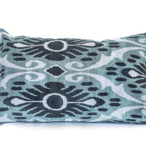 Peut inclure: Un coussin décoratif avec un motif ikat bleu et noir. Le coussin est rectangulaire et a une texture douce et moelleuse.