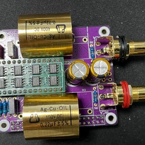 May include: A purple circuit board with gold-colored capacitors and RCA jacks. The board has text that reads "Ag-Cu-OIL 400V DC 0.22µF±5%" and "0.22µF±5%".