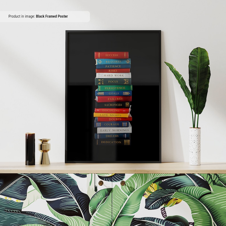 Op de afbeelding: Zwarte gelijst poster met een stapel boeken op een zwarte achtergrond. De boeken hebben verschillende gekleurde ruggen en op elke rug staat een woord gedrukt. De woorden op de ruggen zijn: Succes, Vereist, Geduld, Risico's, Hard werken, Focus, Volharding, Doelen, Mislukkingen, Opofferingen, Discipline, Late avonden, Twijfels, Moed, Vroege ochtenden, Dromen, Toewijding.