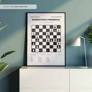 Könnte beinhalten: Ein schwarzer gerahmter Poster mit einem Schachbrett, das die unsterbliche Schachpartie von Rubinstein zeigt. Das Poster enthält die Namen der Spieler, Gersz Rotlewi und Akiba Rubinstein, das Datum der Partie, 1907, und die Anzahl der Züge, 25. Das Poster enthält auch eine Liste der von jedem Spieler ausgeführten Züge.
