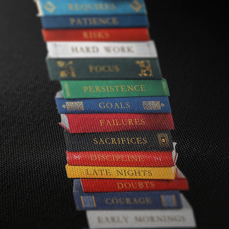 Op de afbeelding: Een stapel boeken met motiverende woorden op de ruggen, waaronder "Geduld", "Risico's", "Hard werken", "Focus", "Volharding", "Doelen", "Mislukkingen", "Opofferingen", "Discipline", "Late avonden", "Twijfels", "Moed" en "Vroege ochtenden".
