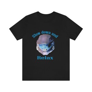 Può includere: T-shirt nera con un grafico di un casco blu e viola e il testo "Slow down and Relax".