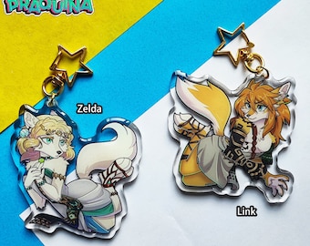 May include: Two acrylic keychains featuring cartoon animal characters. The keychain on the left features a white fox with blonde hair and a blue dress. The keychain on the right features a yellow fox with orange hair and a brown and gold outfit. The text "Zelda" is above the left keychain and "Link" is below the right keychain.