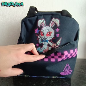 Peut inclure: Sac &agrave; d&eacute;jeuner noir avec un motif &agrave; carreaux rose et blanc. Il repr&eacute;sente un lapin de dessin anim&eacute; avec des yeux rouges et un n&oelig;ud papillon. Le sac a une poche zipp&eacute;e et le texte "Security Breach" en bas.