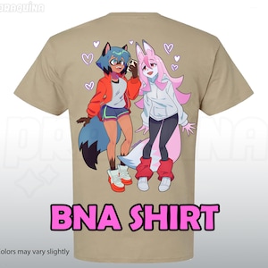 Pode incluir: Camiseta bege com uma ilustração colorida em estilo anime de dois personagens, um com pelo azul e outro rosa. O texto "BNA SHIRT" é rosa. A frase "*colors may vary slightly" está na parte inferior.