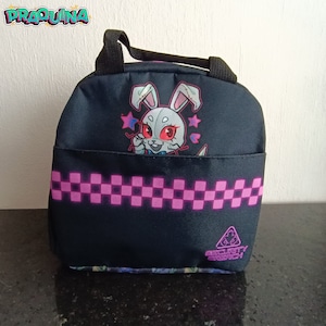 Peut inclure: Sac &agrave; d&eacute;jeuner noir avec un motif &agrave; carreaux rose et blanc. Il repr&eacute;sente un lapin de dessin anim&eacute; avec des yeux rouges et un n&oelig;ud papillon rose. Le sac a une poign&eacute;e noire et le texte "Security Breach" en bas.