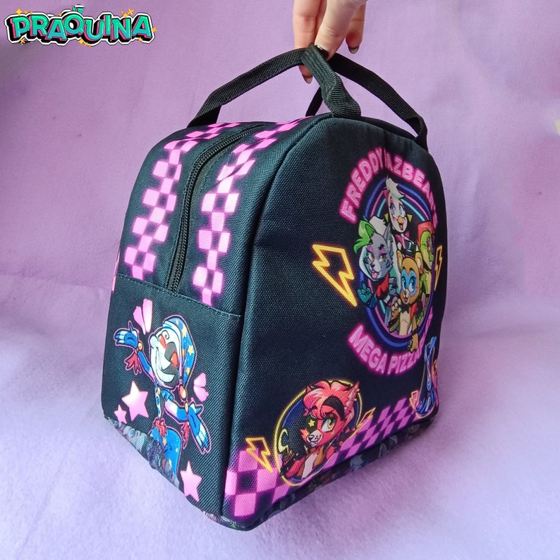 Peut inclure: Sac &agrave; d&eacute;jeuner noir avec un motif &agrave; carreaux rose et noir. Le sac pr&eacute;sente un graphique de personnages du jeu vid&eacute;o "Freddy Fazbear's Mega Pizza" avec le texte "Freddy Fazbear's Mega Pizza".