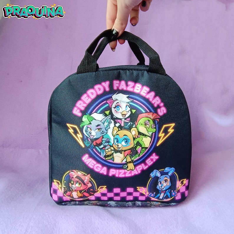 Peut inclure: Sac &agrave; d&eacute;jeuner noir avec un graphisme color&eacute; de cinq personnages de dessin anim&eacute; du jeu vid&eacute;o "Freddy Fazbear's Mega Pizzaplex". Les personnages sont dispos&eacute;s en cercle avec le texte "Freddy Fazbear's Mega Pizzaplex" en lettres n&eacute;on roses.