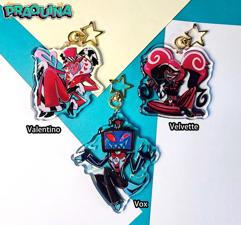 May include: Three acrylic keychains featuring characters from the animated series "Hazbin Hotel". The keychains are shaped like the characters and feature their signature colors and designs. The characters are Valentino, a red demon with a heart-shaped head, Velvette, a red demon with horns and a red dress, and Vox, a blue demon with a television for a head.