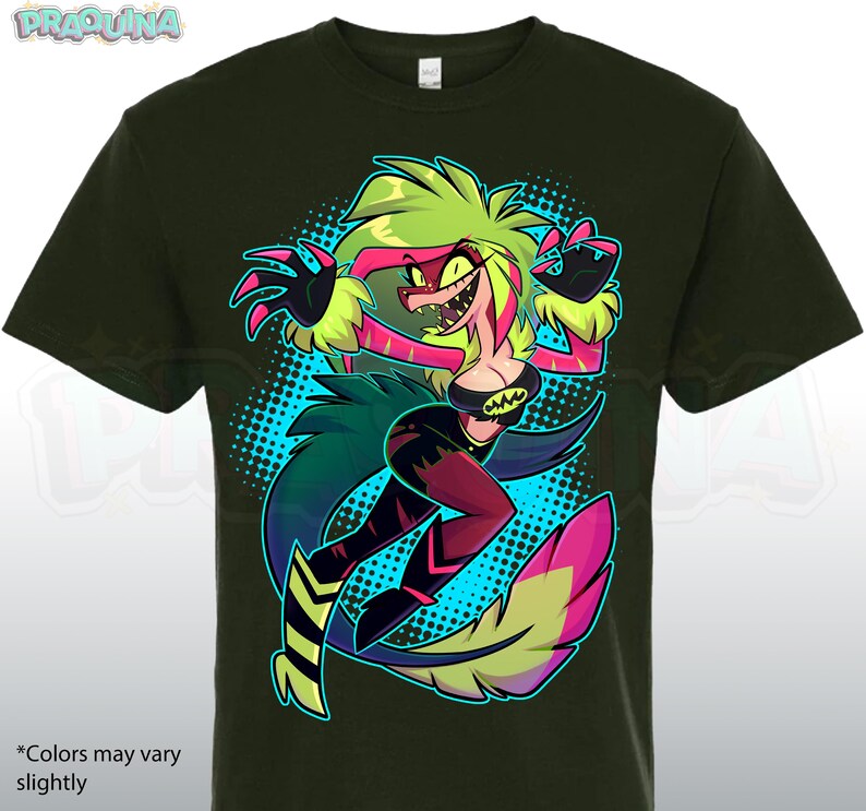 May include: Dark green t-shirt featuring a colorful cartoon character with green, pink, and yellow hair and a black outfit. The character is set against a blue dotted background. The text "*Colors may vary slightly" is at the bottom.