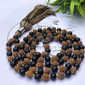 May include: A mala or japa mala prayer bead necklace with black and brown beads. The necklace has a tassel made of brown and black thread.