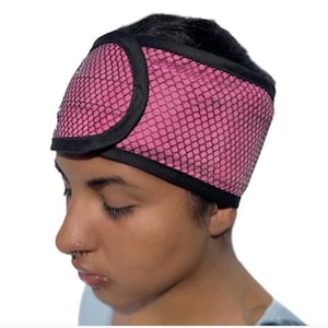 May include: A pink mesh headband with a black trim. The headband is worn on the head and covers the ears. The mesh pattern is a repeating small diamond shape.