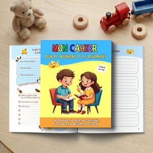 Peut inclure: Un cahier pour enfants intitulé "MON CAHIER POUR LES RÉUNIONS ET LES ASSEMBLÉES" avec des illustrations de deux enfants. La couverture est bleue avec du texte coloré et une image de dessin animé. Le cahier est ouvert pour montrer des pages lignées.
