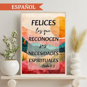 May include: A framed art print with the word "ESPAÑOL" at the top. The artwork features a colorful abstract landscape with text in Spanish that reads "FELICES los que RECONOCEN sus NECESIDADES ESPIRITUALES Mateo 5:3". The print is displayed on a white shelf.