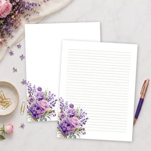Peut inclure: Deux feuilles de papier à lettres blanc ornées d'une illustration florale de roses violettes et de brins de lavande en bas. Une feuille est vierge, tandis que l'autre comporte des lignes horizontales. Un stylo violet et des trombones dorés sont présents.