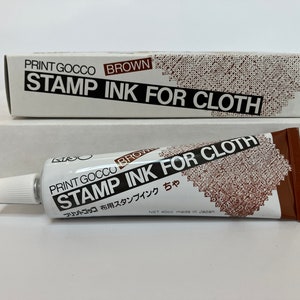 May include: A brown tube of Print Gocco stamp ink for cloth. The tube is labeled "Print Gocco Brown Stamp Ink for Cloth" in English and Japanese. The tube is 400 ml and made in Japan.