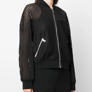 Peut inclure: Veste de bombardier noire avec un motif rayé transparent. La veste est dotée d'une fermeture éclair sur le devant, d'une petite poche zippée et de poignets et d'un ourlet côtelés. Les manches et le haut du dos ont des rayures verticales, tandis que le devant a des rayures diagonales.