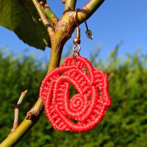 Peut inclure: Boucles d'oreilles en forme de rose rouge crochetées avec un crochet doré.