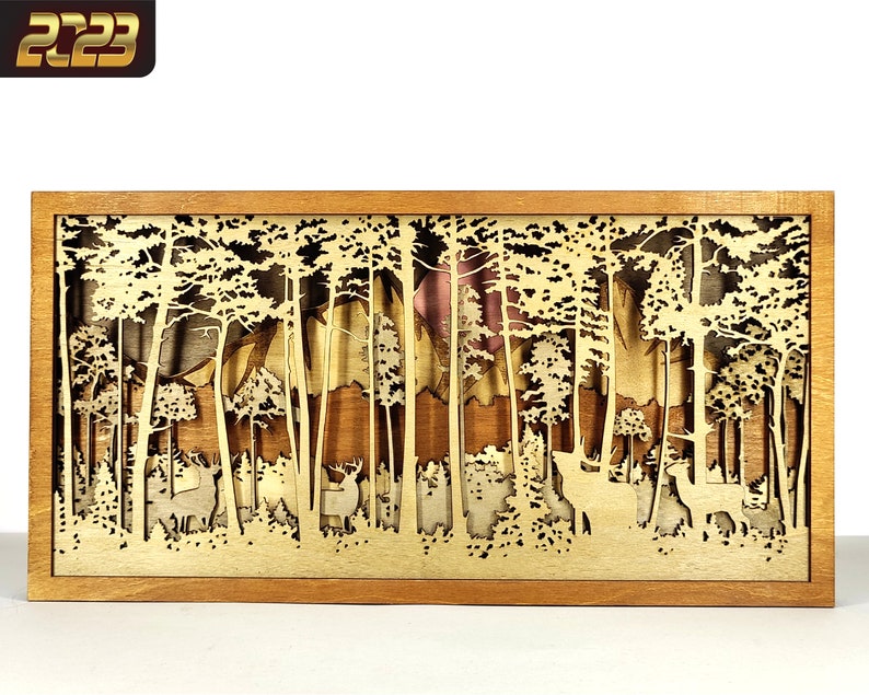 May include: A wooden box with a laser cut design of a forest scene. The scene features trees, mountains, and deer. The box is made of light brown wood and has a natural wood finish.