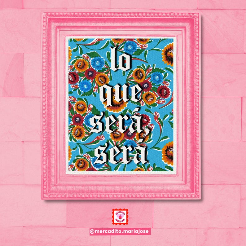 May include: A framed print with a blue background and a floral pattern. The print features the Spanish phrase "lo que ser&aacute;, ser&aacute;" in white lettering.