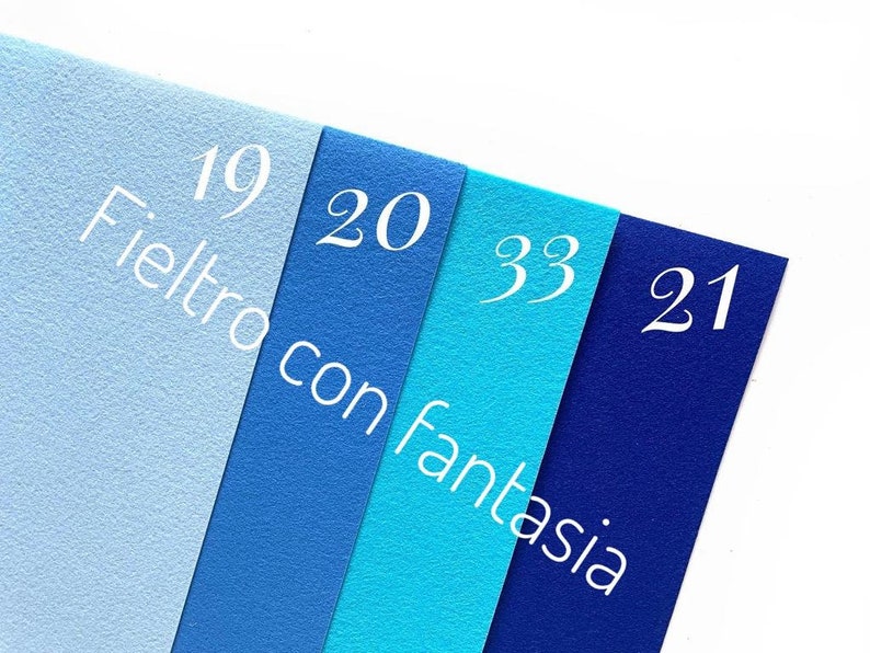 May include: Four felt fabric swatches in shades of blue, labeled with numbers 19, 20, 33, and 21. The text "Feltro con fantasia" is printed on the swatches.