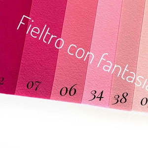 May include: A color chart of felt fabric swatches in various shades of pink, labeled with numbers. The text "Feltro con fantasia" is written in black across the top of the swatches.