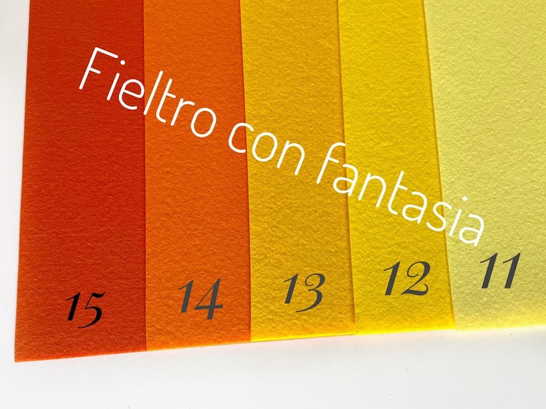 May include: Five strips of felt fabric in various shades of orange and yellow. The felt is labeled with numbers 11, 12, 13, 14, and 15. The text "Felt with fantasy" is written diagonally across the fabric.