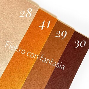 May include: Four samples of felt fabric in different shades of brown, beige, and orange. The felt is labeled with numbers 28, 41, 29, and 30. The text "Fieltro con fantasia" is written in white on the felt.