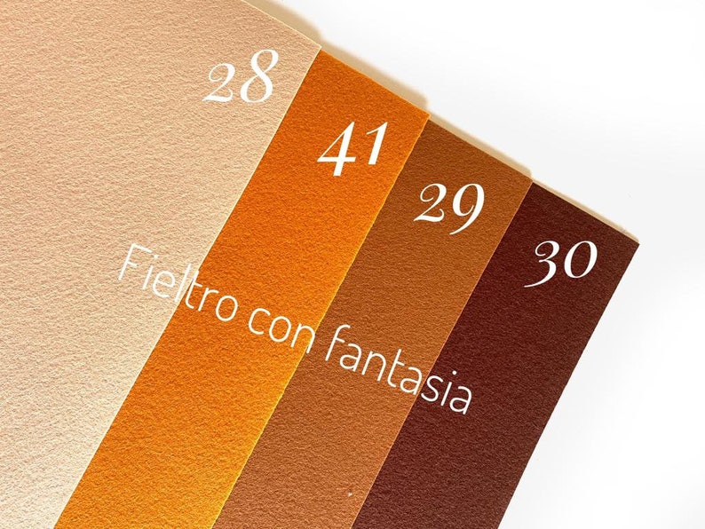 May include: Four samples of felt fabric in different shades of brown, beige, and orange. The felt is labeled with numbers 28, 41, 29, and 30. The text "Fieltro con fantasia" is written in white on the felt.