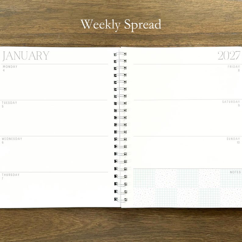 Puede incluir: Una agenda de espiral abierta en una vista semanal para enero de 2027. Las p&aacute;ginas blancas presentan texto en negro que incluye el encabezado Weekly Spread, el mes de enero, el a&ntilde;o 2027 y los d&iacute;as de la semana con una secci&oacute;n de notas.