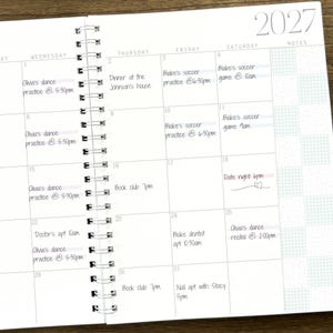 May include: A 2027 spiral-bound monthly planner with white pages and black grid lines. The calendar features handwritten entries for various appointments, including dance practice, soccer games, book club, and doctor visits, with a notes column on the right.