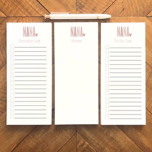 May include: Three white notepad sets with pink and white text that reads "NANA" with a small pink heart. The notepads are labelled "Grocery List", "Notes", and "To Do List".