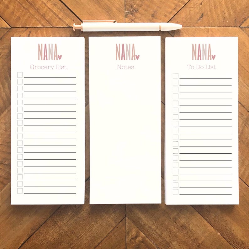 May include: Three white notepad sets with pink and white text that reads "NANA" with a small pink heart. The notepads are labelled "Grocery List", "Notes", and "To Do List".