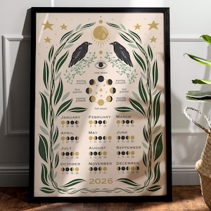 Op de afbeelding: Ingelijste kunstprint met een hemels ontwerp, met twee zwarte raven, maanfasen en een kalender voor 2026. Het kunstwerk bevat botanische elementen, sterren en een zon in een neutraal kleurenpalet.