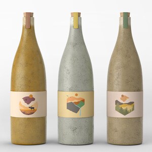 May include: Three glass bottles with cork tops and labels featuring nature-inspired designs. The bottles are in various shades of brown, gray, and green. The labels feature illustrations of a mountain range, a deer, and a forest.
