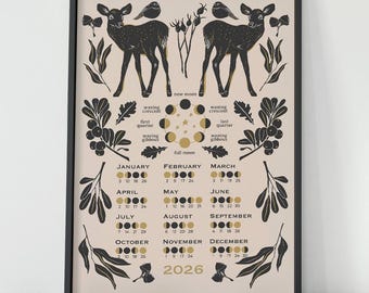 May include: A framed art print featuring a black and gold 2026 calendar with deer and bird illustrations. The calendar displays moon phases and dates for each month. The artwork has a beige background and a black frame.