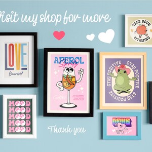 May include: A collection of colourful wall art prints featuring various designs, including a peach with the text "Take Your Vitalting", a frog with the text "Stay Positive", a cocktail glass with the text "Aperol Spritz", and a watermelon with the text "What Makes You Happy".
