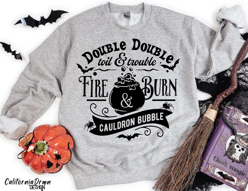 Pu&ograve; includere: Felpa grigia con un design grafico nero che presenta un calderone, pipistrelli e il testo "Double Double toil & trouble Fire Burn & Cauldron Bubble".