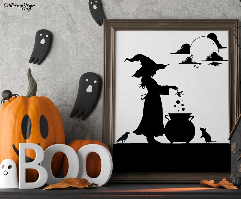 May include: Halloween-themed decor featuring a framed silhouette art print of a witch, cauldron, and full moon. Orange pumpkin with a carved face and the word "BOO" in white letters. Black ghost and spider decorations complete the spooky scene.