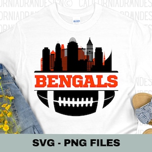May include: A white t-shirt with a black and orange design of the Cincinnati skyline and a football with the word "BENGALS" in orange letters.