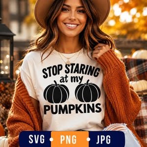 May include: A white short-sleeved t-shirt featuring black text that reads STOP STARING at my PUMPKINS, accompanied by two black pumpkin illustrations. The shirt is worn under a thick, textured, burnt orange open-front cardigan sweater.