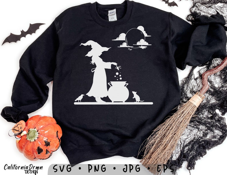 May include: Black sweatshirt featuring a white graphic of a witch stirring a cauldron, with a cat and bats. The design includes a moon and clouds, perfect for Halloween. The words "California Drmn Design" are at the bottom.