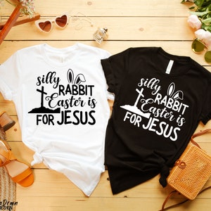 May include: Two t-shirts with a black and white graphic design. The design features a cross, bunny ears, and the text "silly rabbit Easter is for Jesus".