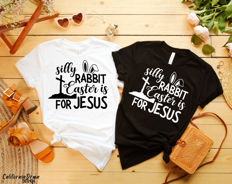 May include: Two t-shirts with a black and white graphic design. The design features a cross, bunny ears, and the text "silly rabbit Easter is for Jesus".