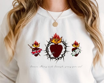 May include: White sweatshirt with a graphic of three flaming hearts with thorns and the text "Jesus, Mary and Joseph, pray for us!"
