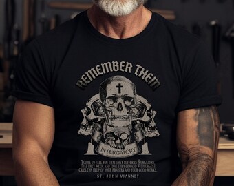 Puede incluir: Camiseta negra con un gráfico de calaveras y una cruz, con el texto "Remember Them In Purgatory" y "St. John Vianney".
